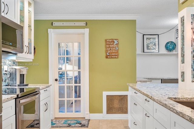 7306 NW 95th Way, Tamarac, FL 33321 - kitchen with stainless steel appliances, ornamental molding, light stone countertops, white cabinetry, and glass insert cabinets
