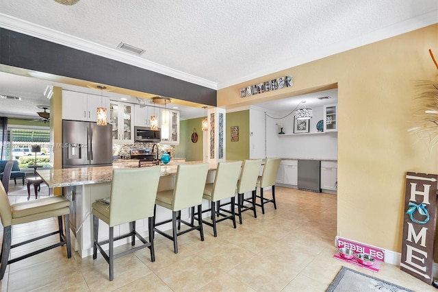 7306 NW 95th Way, Tamarac, FL 33321 - kitchen featuring stainless steel appliances, a breakfast bar area, backsplash, a textured ceiling, and white cabinets