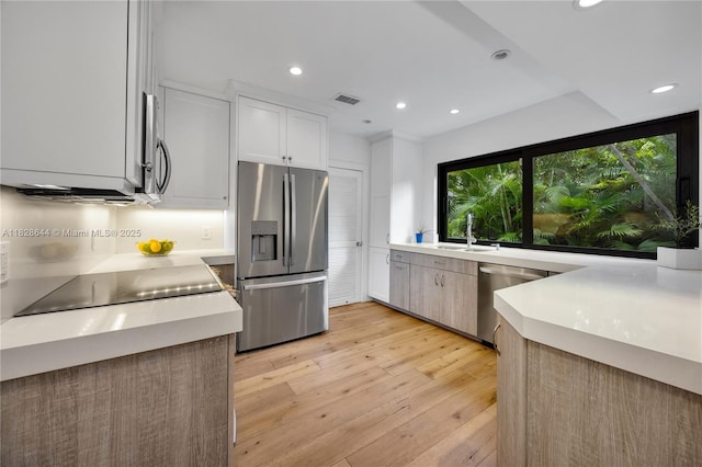 2427 Tequesta Ln, Miami, FL 33133 - kitchen with appliances with stainless steel finishes, light wood-type flooring, recessed lighting, light countertops, and white cabinets