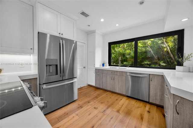2427 Tequesta Ln, Miami, FL 33133 - kitchen featuring appliances with stainless steel finishes, light wood finished floors, recessed lighting, light countertops, and white cabinetry