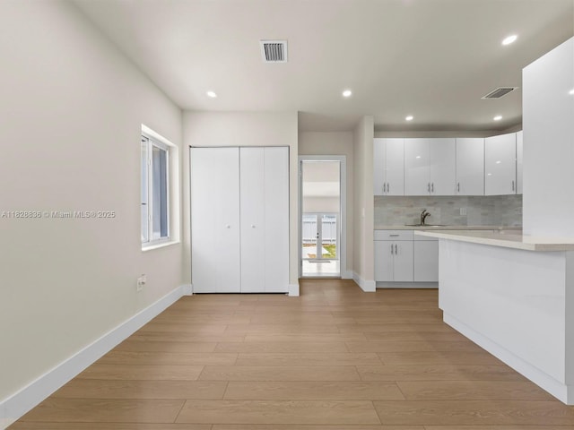 3455 E 1st Ct, Hialeah, FL 33013 - kitchen featuring light countertops, white cabinetry, light wood-style floors, tasteful backsplash, and recessed lighting
