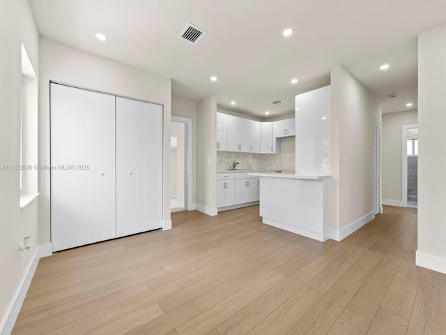 3455 E 1st Ct, Hialeah, FL 33013 - kitchen featuring light countertops, light wood-style flooring, white cabinetry, decorative backsplash, and recessed lighting