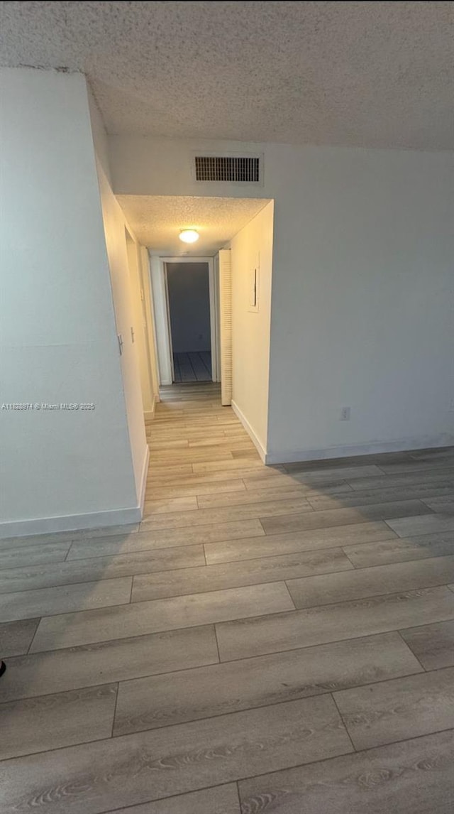 8075 NW 7th St Unit 318, Miami, FL 33126 - hallway with light wood-style floors and a textured ceiling