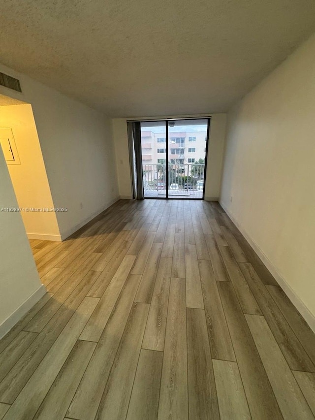 8075 NW 7th St Unit 318, Miami, FL 33126 - empty room featuring wood finished floors, expansive windows, and a textured ceiling