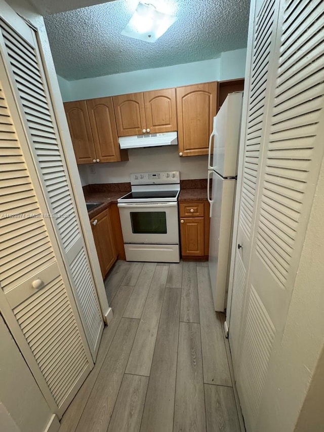 8075 NW 7th St Unit 318, Miami, FL 33126 - kitchen featuring white appliances, under cabinet range hood, light wood-style flooring, dark countertops, and a textured ceiling