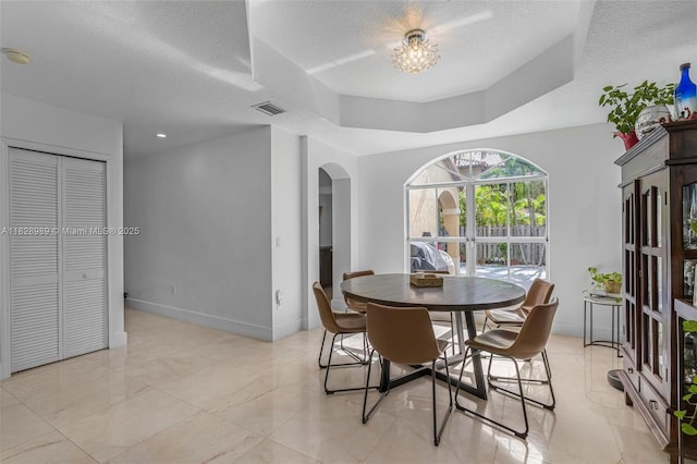 2620 SW 150th Ct, Miami, FL 33185 - dining room with arched walkways, a textured ceiling, a raised ceiling, and a chandelier