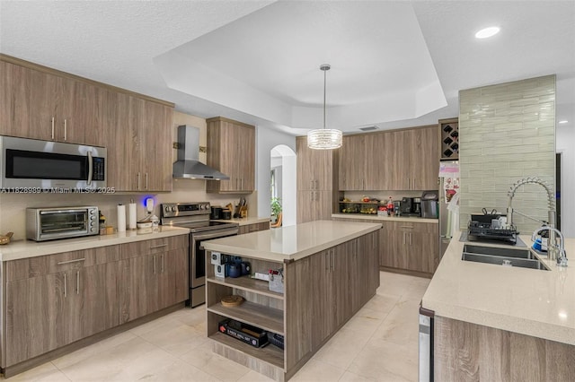 2620 SW 150th Ct, Miami, FL 33185 - kitchen featuring stainless steel appliances, wall chimney exhaust hood, a tray ceiling, arched walkways, and open shelves