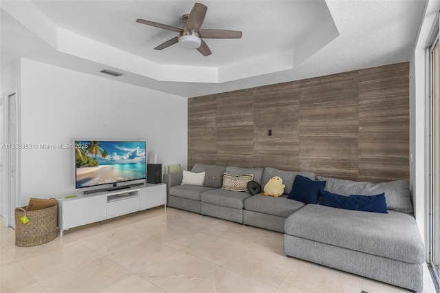 2620 SW 150th Ct, Miami, FL 33185 - living room featuring a raised ceiling, a ceiling fan, an accent wall, and a textured ceiling