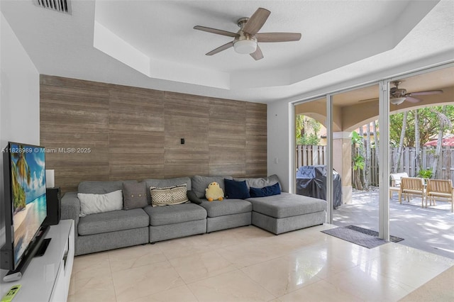 2620 SW 150th Ct, Miami, FL 33185 - tiled living room with ceiling fan, an accent wall, a tray ceiling, and tile walls