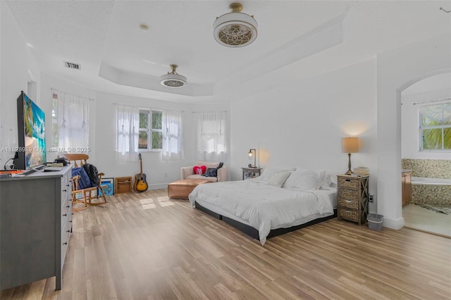 2620 SW 150th Ct, Miami, FL 33185 - bedroom with light wood finished floors, a raised ceiling, arched walkways, and connected bathroom