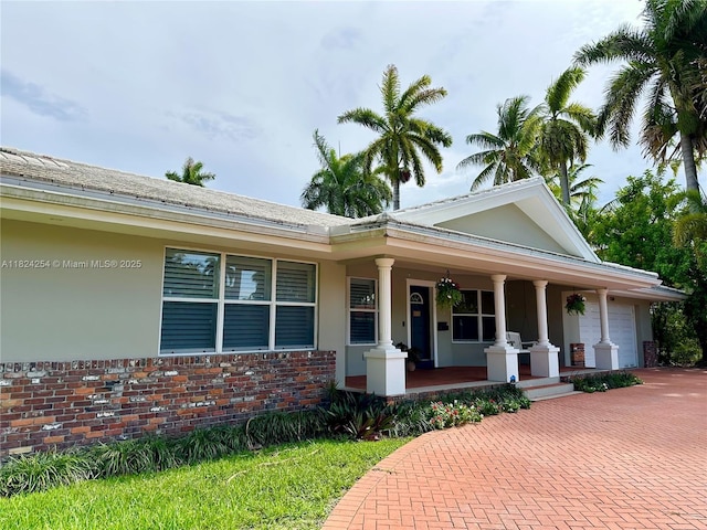 1330 Harrison St, Hollywood, FL 33019 - view of front facade with covered porch, a garage, decorative driveway, brick siding, and stucco siding