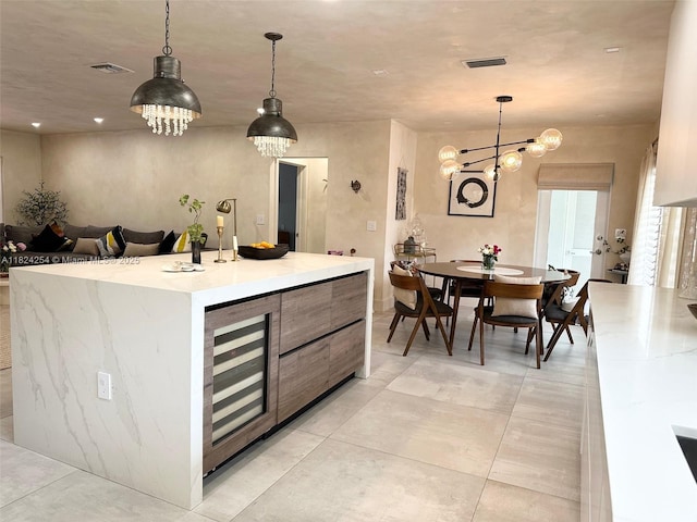 1330 Harrison St, Hollywood, FL 33019 - kitchen with beverage cooler, light countertops, a kitchen island with sink, decorative light fixtures, and a chandelier