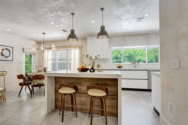 1330 Harrison St, Hollywood, FL 33019 - kitchen with healthy amount of natural light, white cabinetry, light countertops, a breakfast bar, and recessed lighting