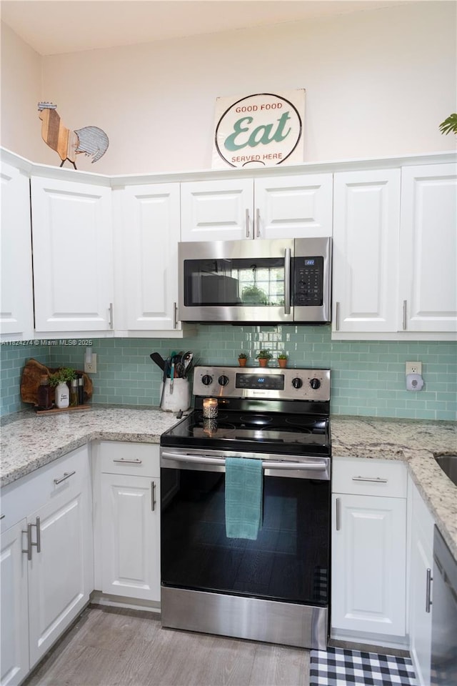 10631 NW 14th St Unit 212, Plantation, FL 33322 - kitchen with appliances with stainless steel finishes, white cabinets, backsplash, and light wood-style floors