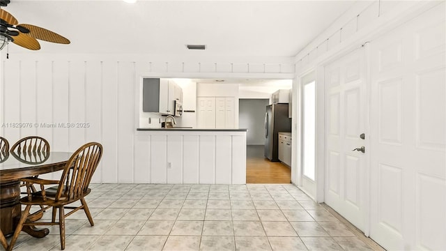 1482 SE Manth Ln, Port St Lucie, FL 34983 - kitchen featuring dark countertops, appliances with stainless steel finishes, ceiling fan, a peninsula, and light tile patterned floors