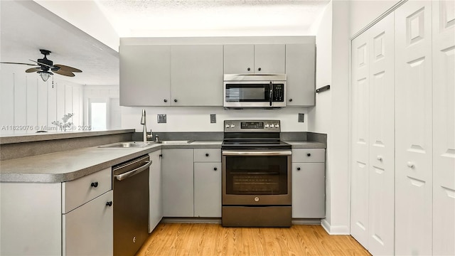 1482 SE Manth Ln, Port St Lucie, FL 34983 - kitchen featuring appliances with stainless steel finishes, light wood-type flooring, a ceiling fan, a peninsula, and gray cabinets