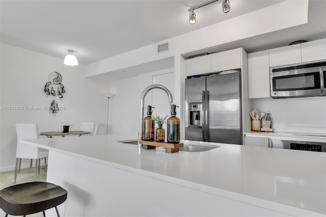 4250 Biscayne Blvd Unit 1217, Miami, FL 33137 - kitchen with appliances with stainless steel finishes, light countertops, white cabinetry, modern cabinets, and a kitchen breakfast bar