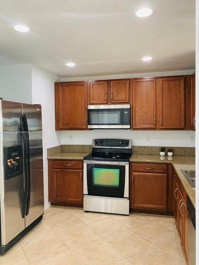 5907 Glasgow Way, Tamarac, FL 33321 - kitchen featuring stainless steel appliances, a textured ceiling, recessed lighting, brown cabinetry, and light tile patterned floors