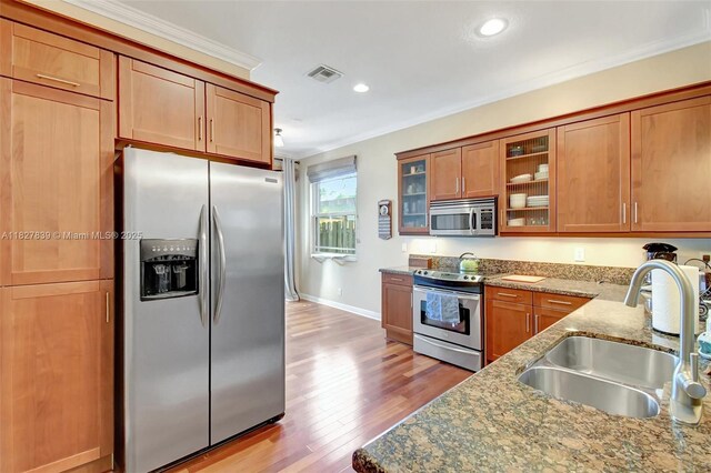 1110 SE 4th Ave, Fort Lauderdale, FL 33316 - kitchen featuring appliances with stainless steel finishes, ornamental molding, stone counters, light wood finished floors, and brown cabinets