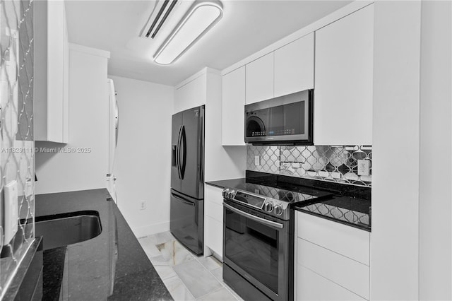 10275 Collins Ave Unit 1035, Bal Harbour, FL 33154 - kitchen with appliances with stainless steel finishes, dark stone countertops, white cabinetry, tasteful backsplash, and light marble finish floors