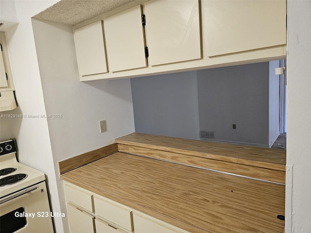 907 NE 199th St Unit 106, Miami, FL 33179 - kitchen featuring white electric range, white cabinetry, ventilation hood, and light countertops