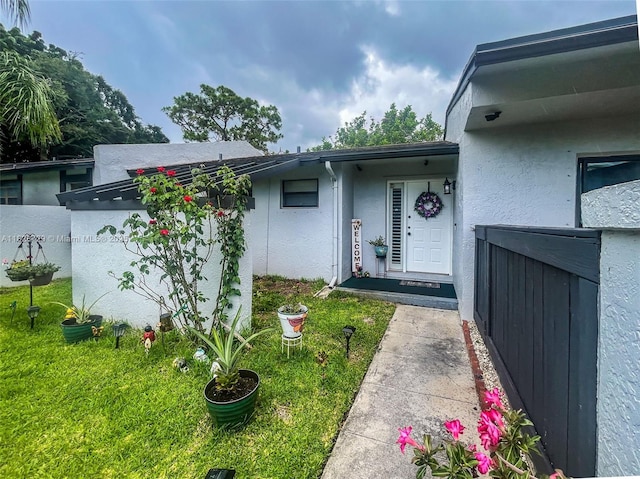 61 W Seminole Ct W, Royal Palm Beach, FL 33411 - view of exterior entry featuring stucco siding and a lawn
