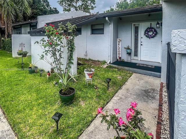 61 W Seminole Ct W, Royal Palm Beach, FL 33411 - doorway to property with stucco siding and a yard