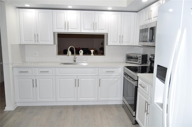 700 SW 128th Ave Unit 106C, Pembroke Pines, FL 33027 - kitchen featuring appliances with stainless steel finishes, white cabinets, light countertops, light wood finished floors, and recessed lighting