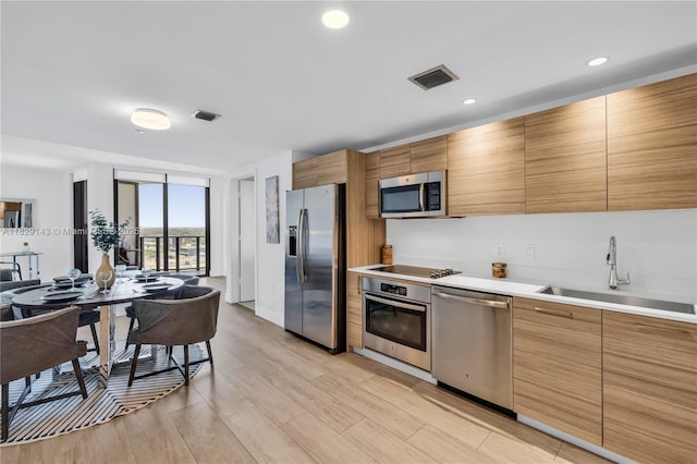 121 NE 34th St Unit 1514, Miami, FL 33137 - kitchen featuring appliances with stainless steel finishes, light countertops, light wood-style floors, brown cabinets, and recessed lighting