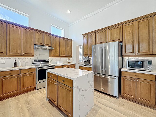 4268 SW 141st Ave, Davie, FL 33330 - kitchen featuring appliances with stainless steel finishes, under cabinet range hood, brown cabinets, crown molding, and light wood-style floors