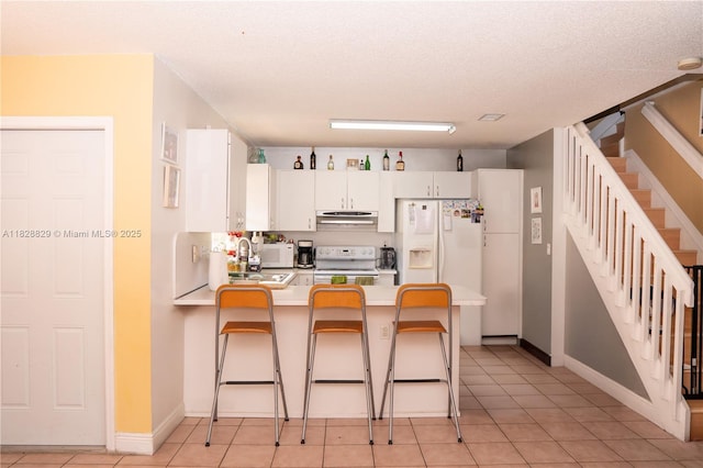 7081 SW 158th Ct, Miami, FL 33193 - kitchen featuring white appliances, under cabinet range hood, a peninsula, white cabinetry, and a kitchen breakfast bar