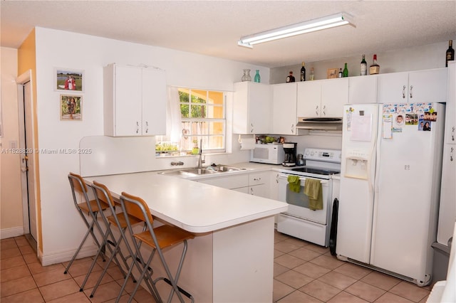7081 SW 158th Ct, Miami, FL 33193 - kitchen with white appliances, under cabinet range hood, a peninsula, light countertops, and light tile patterned flooring