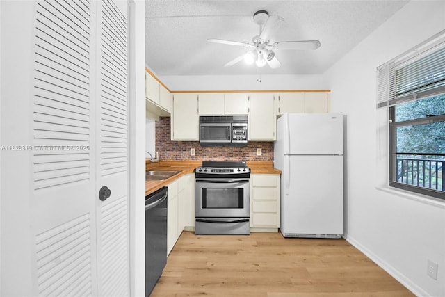 10501 W Broward Blvd Unit 304, Plantation, FL 33324 - kitchen featuring appliances with stainless steel finishes, light wood-style flooring, decorative backsplash, a ceiling fan, and a textured ceiling
