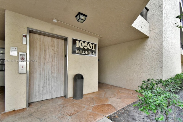 10501 W Broward Blvd Unit 304, Plantation, FL 33324 - view of exterior entry with stucco siding and elevator