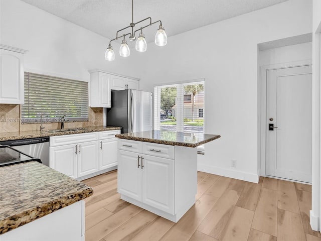 10370 NW 11th St, Plantation, FL 33322 - kitchen with freestanding refrigerator, dark stone countertops, decorative backsplash, white cabinetry, and light wood finished floors
