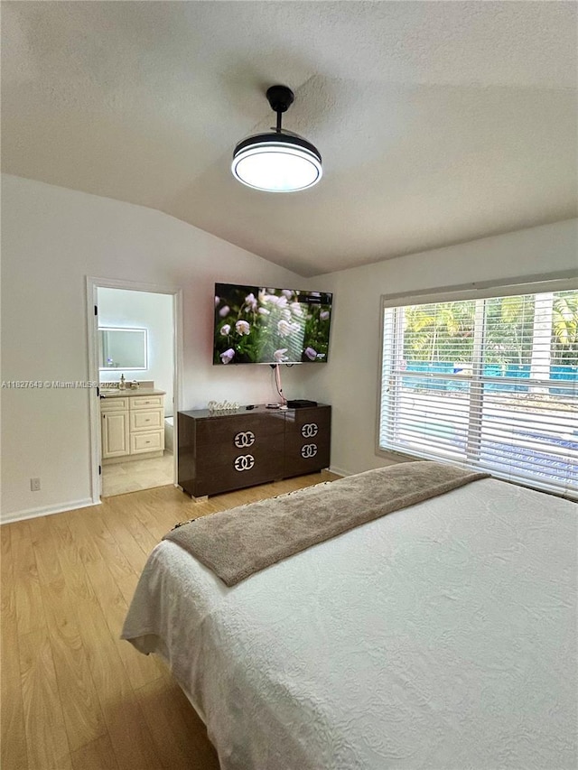 1084 Aspri Way, Riviera Beach, FL 33418 - bedroom featuring vaulted ceiling, light wood-style floors, a textured ceiling, and ensuite bath