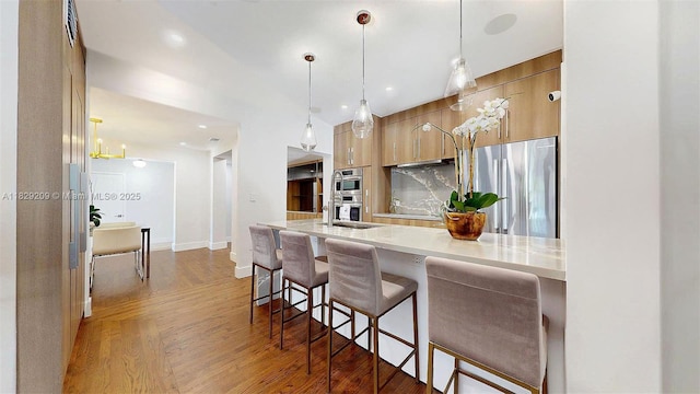 1222 Cortez St, Coral Gables, FL 33134 - kitchen with stainless steel appliances, modern cabinets, wood finished floors, a breakfast bar area, and light countertops