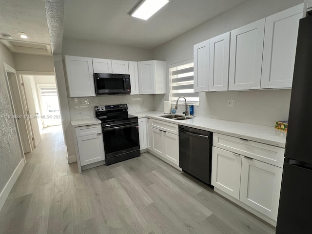 1214 NE 180th St, North Miami Beach, FL 33162 - kitchen featuring black appliances, white cabinets, light wood finished floors, tasteful backsplash, and light stone counters