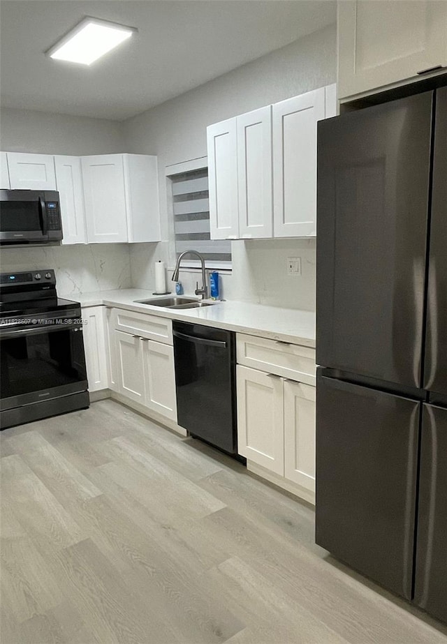 1214 NE 180th St, North Miami Beach, FL 33162 - kitchen with black appliances, light wood finished floors, light countertops, and white cabinets
