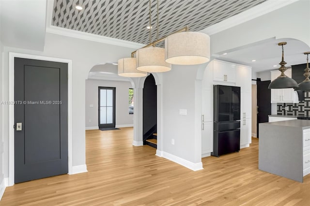 1145 SW 20th Ave, Miami, FL 33135 - kitchen featuring freestanding refrigerator, arched walkways, white cabinets, crown molding, and light wood finished floors