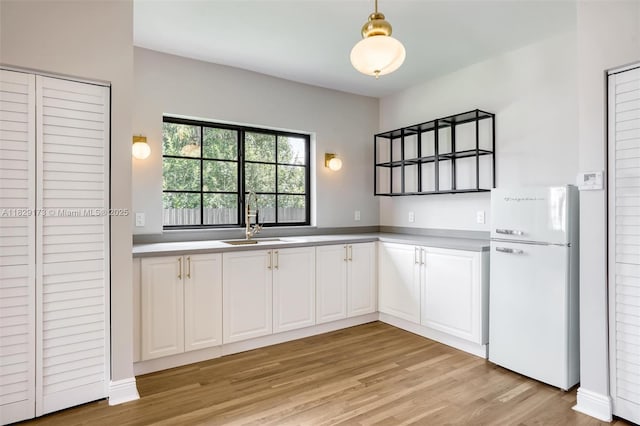 1145 SW 20th Ave, Miami, FL 33135 - kitchen with freestanding refrigerator, light wood-style flooring, white cabinets, pendant lighting, and light countertops