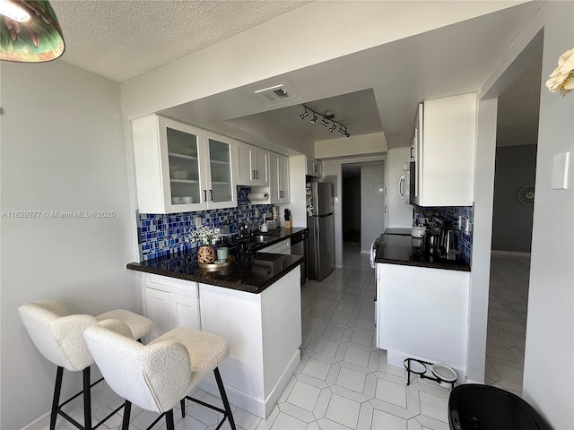 18011 Biscayne Blvd Unit 805, Aventura, FL 33160 - kitchen featuring appliances with stainless steel finishes, dark countertops, white cabinetry, glass insert cabinets, and a textured ceiling