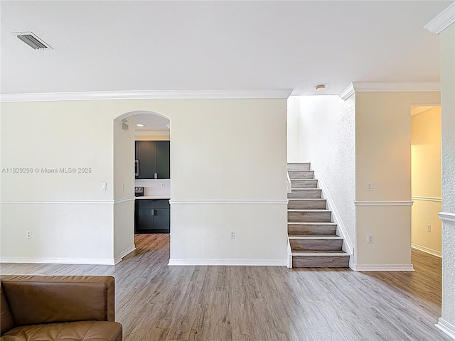 1568 SE 20th Ter, Homestead, FL 33035 - unfurnished living room featuring ornamental molding, light wood finished floors, arched walkways, and stairs