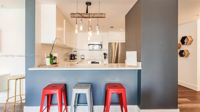 3250 NE 1st Ave Unit 1101, Miami, FL 33137 - kitchen with stainless steel refrigerator, a breakfast bar, wood finished floors, and a peninsula