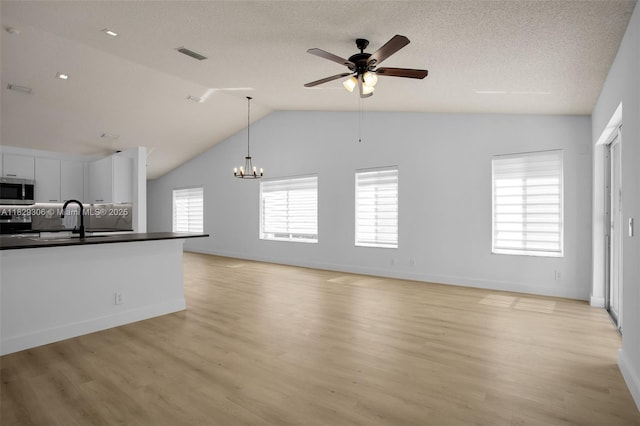 1611 Palermo Dr, Weston, FL 33327 - unfurnished living room featuring a ceiling fan, a chandelier, light wood finished floors, lofted ceiling, and a textured ceiling