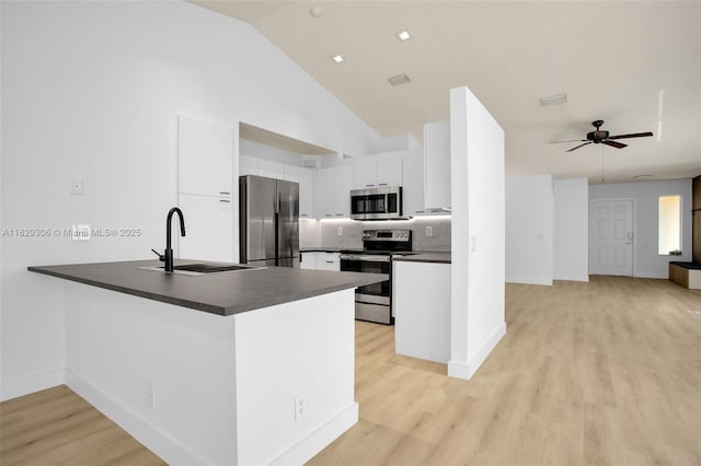 1611 Palermo Dr, Weston, FL 33327 - kitchen with appliances with stainless steel finishes, dark countertops, a peninsula, white cabinetry, and light wood-style flooring
