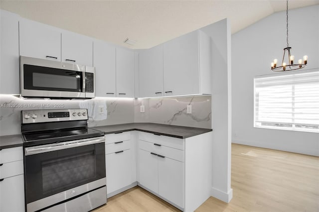 1611 Palermo Dr, Weston, FL 33327 - kitchen with stainless steel appliances, dark countertops, a chandelier, light wood-style floors, and tasteful backsplash