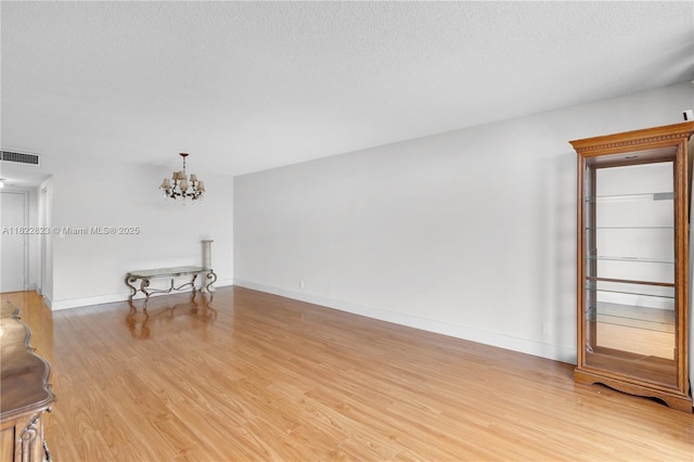600 Three Islands Blvd Unit 310, Hallandale Beach, FL 33009 - unfurnished living room with a chandelier, light wood-style floors, and a textured ceiling