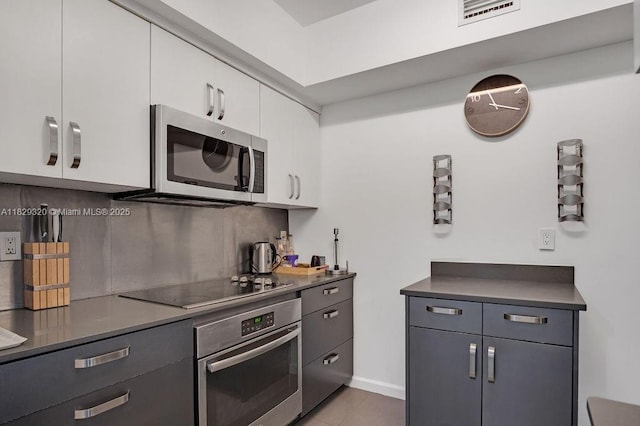 747 Michigan Ave Unit 201, Miami Beach, FL 33139 - kitchen featuring stainless steel appliances, white cabinetry, tile patterned floors, and dark countertops