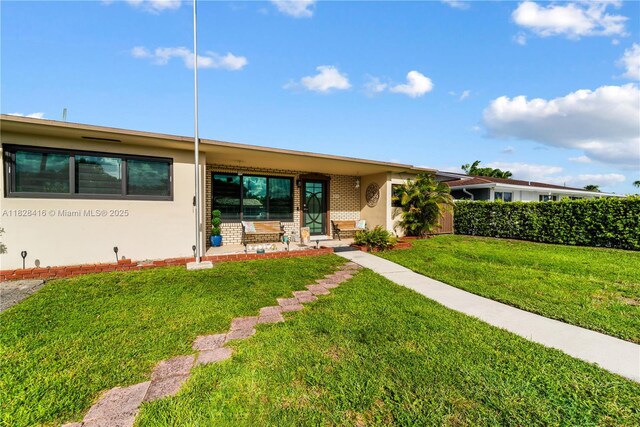 8065 W 14th Ct, Hialeah, FL 33014 - view of front facade featuring covered porch, a front yard, stucco siding, and brick siding